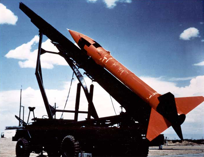 A rocket, painted orange, on a mobile launcher. Virca 1960's.